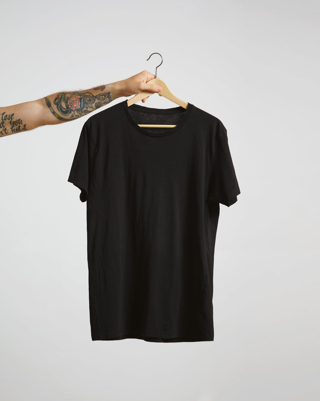 Black t-shirt on a hanger against a plain background