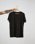 Black t-shirt on a hanger against a plain background