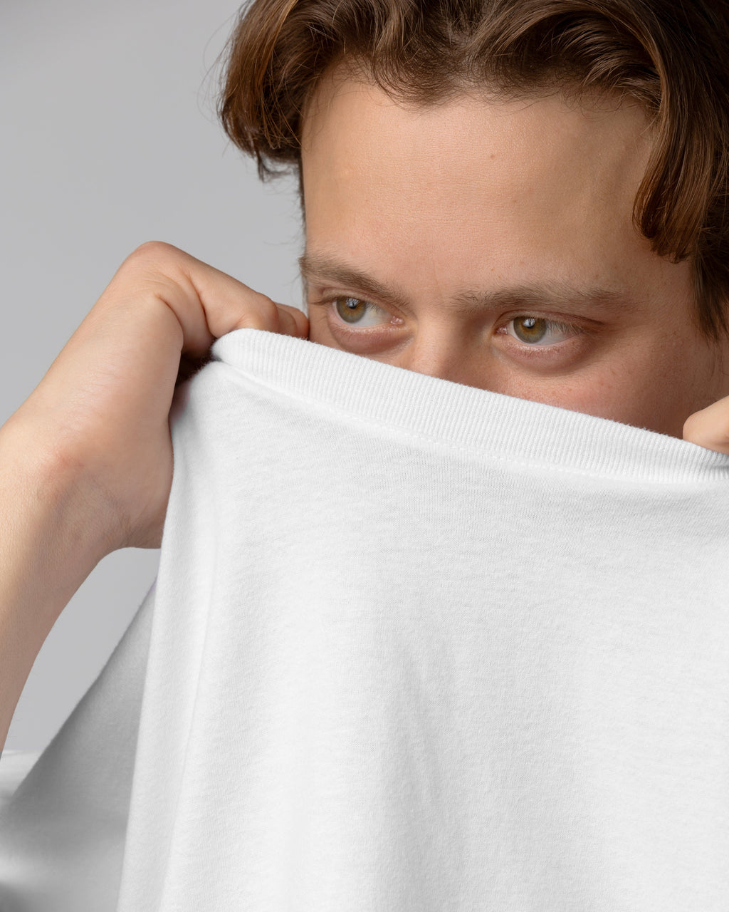 Person holding a white towel over their face against a gray background